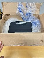 Open cardboard box showing multiple black Dermalogica notebooks with packaging material