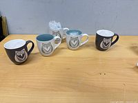 Five owl motif mugs arranged on table