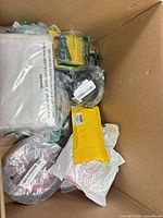 Top view of box showing white bag, yellow envelope, blister pack, two black coils