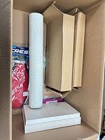 Top view of box showing light grey roll, sealed red Crest item, cardboard inserts and white gift box