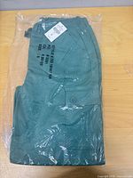 Full view of folded green cargo pants sealed in plastic showing printed style and size information