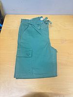 Folded green pants showing flap pocket and overall color