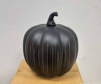 Front view of black glass pumpkin showing matte finish and glitter stripes