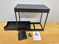 Assembled organizer showing perforated top shelf, frame, bottom drawer tray, hardware packet, curved handle and instruction card