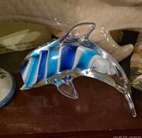 Left-side view of dolphin figurine showing blue and white swirls and clear glass body