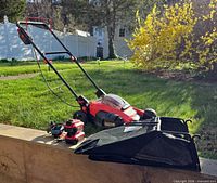 Craftsman V20 lawn mower with grass catcher, two batteries and charger displayed outdoors