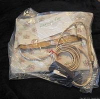Heating pad folded in plastic bag showing cord and controller