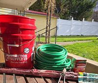Full lot view showing buckets, hose, plant food, stakes