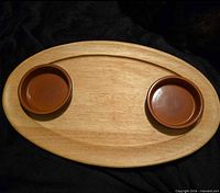 Top view of wooden platter with two terracotta bowls in wells