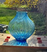 Full view of blue ribbed glass vase in natural light