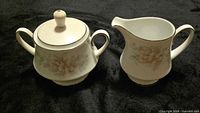 Sugar bowl with lid and creamer displaying floral pattern and platinum trim