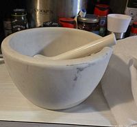 White porcelain mortar with porcelain pestle inside showing chip and wear