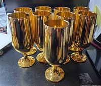 Nine gold mirrored goblets grouped on table