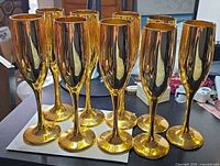 Front and back rows of 11 gold champagne flutes