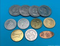 Overall view of four Churchill crowns and seven assorted Canadian tokens on blue background