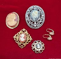 Group shot of four brooches and pair of earrings on red background