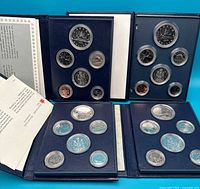 Four blue specimen coin books open displaying coins