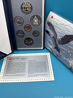 Front view of set in presentation booklet alongside COA and sleeve