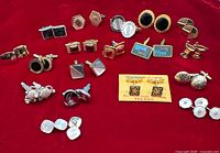 Overview of entire group of vintage cufflinks arranged on red fabric