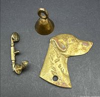 Brass bell, dog head plate, and telephone receiver laid out