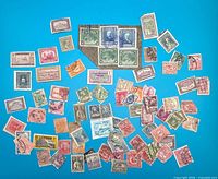 Full layout of roughly 80 assorted used stamps on blue background