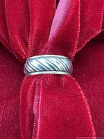 Sterling silver ribbed band ring displayed on red velvet