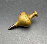 Side view of brass plumb bob showing overall form and tip