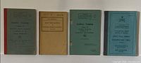 Four military manuals standing upright showing covers