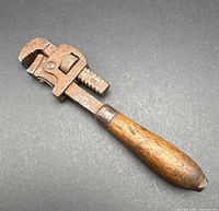 Full view of pipe wrench showing wooden handle and steel head