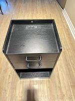 Full view of black cabinet showing top tray, power module, drawers, open shelf