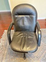 Front view of black faux leather office chair showing seat, backrest and armrests