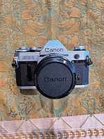 Front view showing Canon AE-1 body with lens cap attached