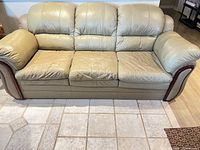 Front view of green bonded leather sofa showing three seats and wood trim