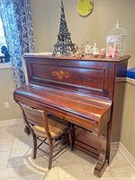 Full view of mahogany upright piano with chair