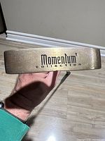 Sole of putter showing Momentum Collection logo