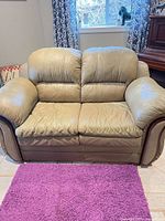 Front view of olive green faux leather loveseat showing overall design and condition