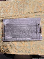 Top view of rectangular gray stone tray with brass handles