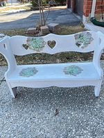 Front view of white wooden child bench with heart cutouts and floral succulents