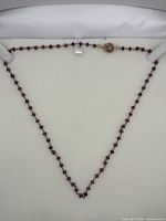 Full view of amethyst bead necklace arranged in box showing beads and gold clasp