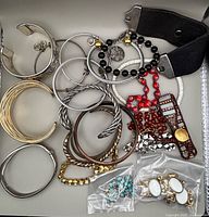 Overview of assorted bangles, beaded pieces, leather cuff and loose link bags