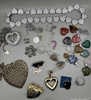 Overall view of all jewellery pieces laid out, showing heart bracelet, pendants, necklaces, earrings, rings and stone hearts