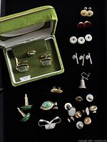 Open box showing jade cufflinks and tie bar plus surrounding studs, cufflinks and tie bar on black background