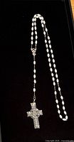 Entire rosary laid out showing beads, chain and crystal cross