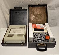 Both carrying cases open showing Zeiss Ikon projector with accessories and Dymo reader