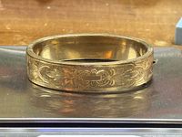 Overall view of ornate gold-tone etched hinged bangle