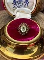 Full view of ring in presentation case showing stone colour and ornate halo