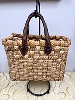 Front view of rectangular woven straw tote with leather handles
