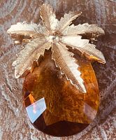 Front view showing gold-tone leaf crown and amber crystal body