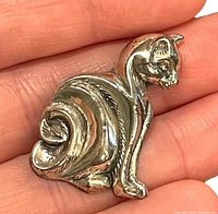 front view of sterling silver cat brooch in hand for scale