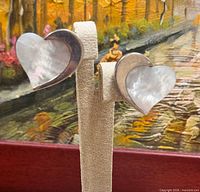 Front view of both heart clip-on earrings on stand